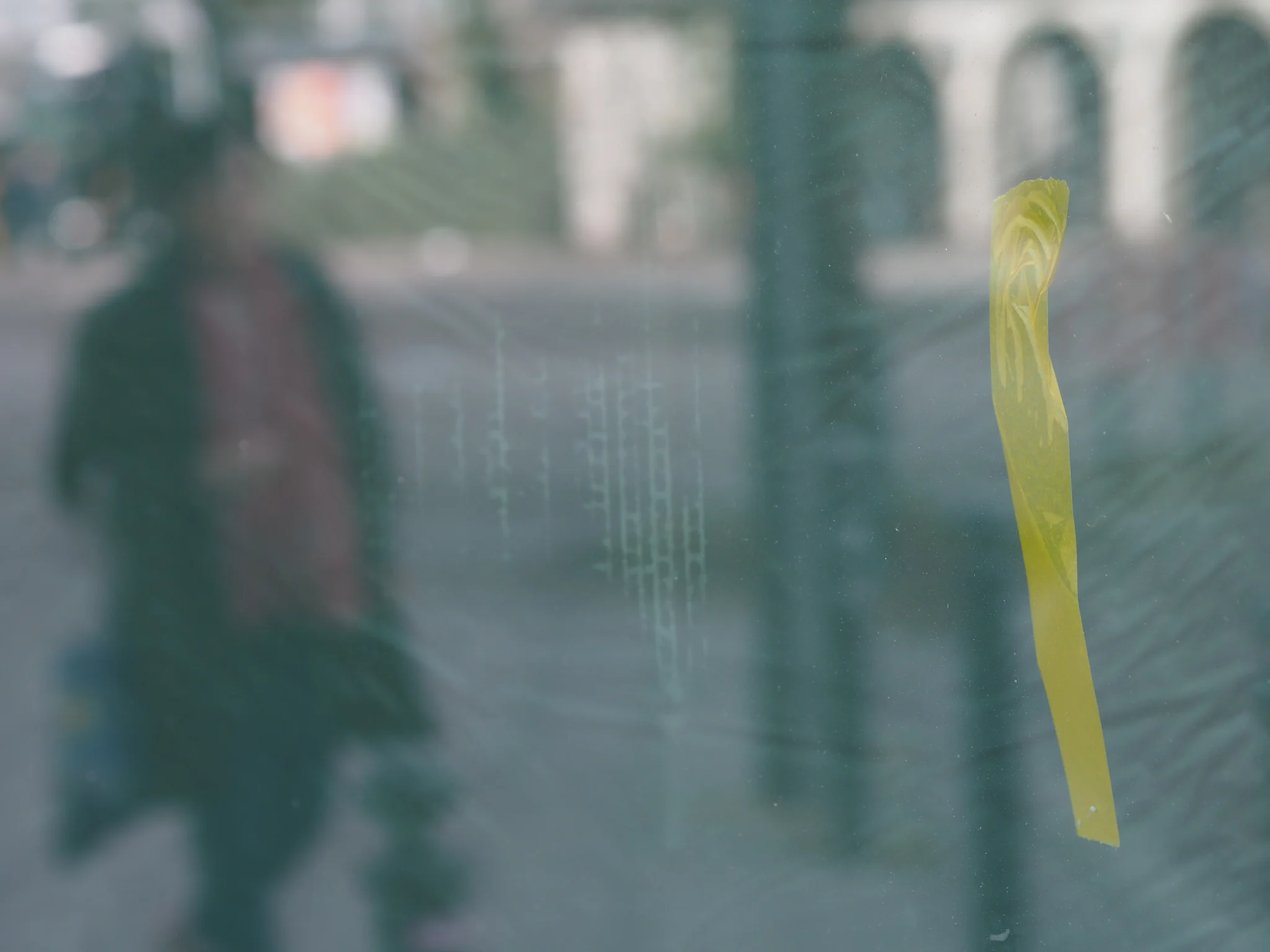 Impressionistic composition of passer-by with yellow tape on window